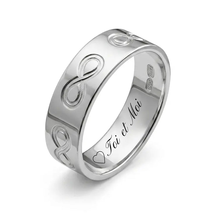 Gros plan détaillé d'une bague alliance pour homme en argent 925 rhodié, large de 6mm. La photo montre clairement les motifs de l'infini gravés en relief tout autour de l'anneau, personnalisable à l'intérieur de l'anneau.