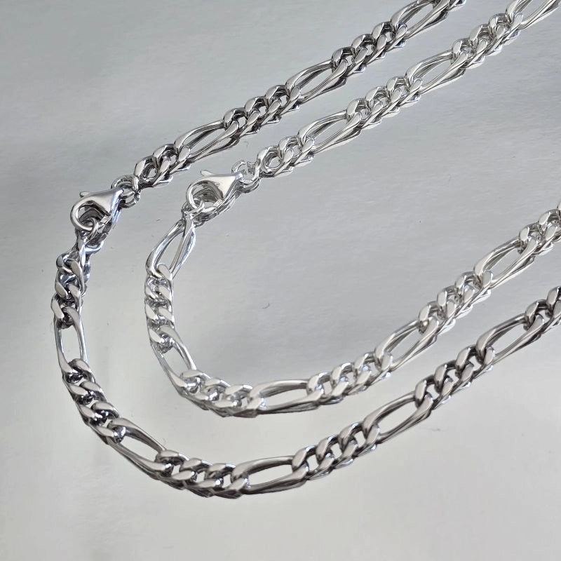 Comparaison visuelle entre chaîne homme argent massif rhodié (plus sombre) et argent massif blanc (traditionnel) maille Figaro 3 mm alternée.