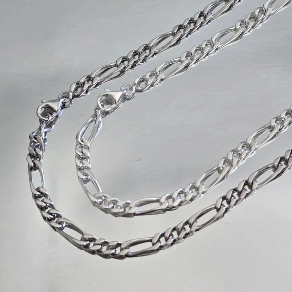 Comparaison visuelle entre chaîne homme argent massif rhodié (plus sombre) et argent massif blanc (traditionnel) maille Figaro 3 mm alternée.
